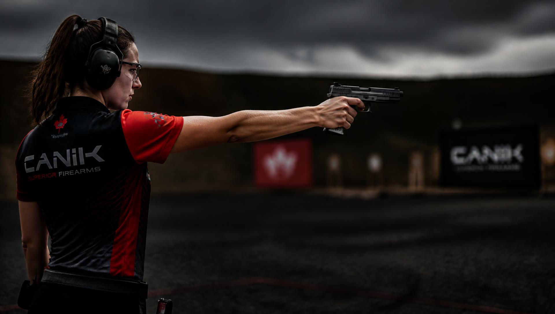 Atleta de tiro esportivo em treinamento no estande, com protetor auricular e óculos de segurança